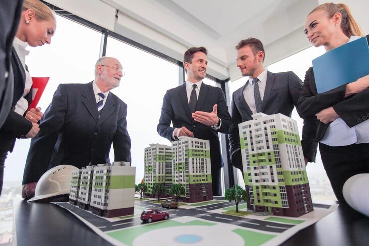 Property team reviewing architectural models of apartment developments during strategic planning meeting