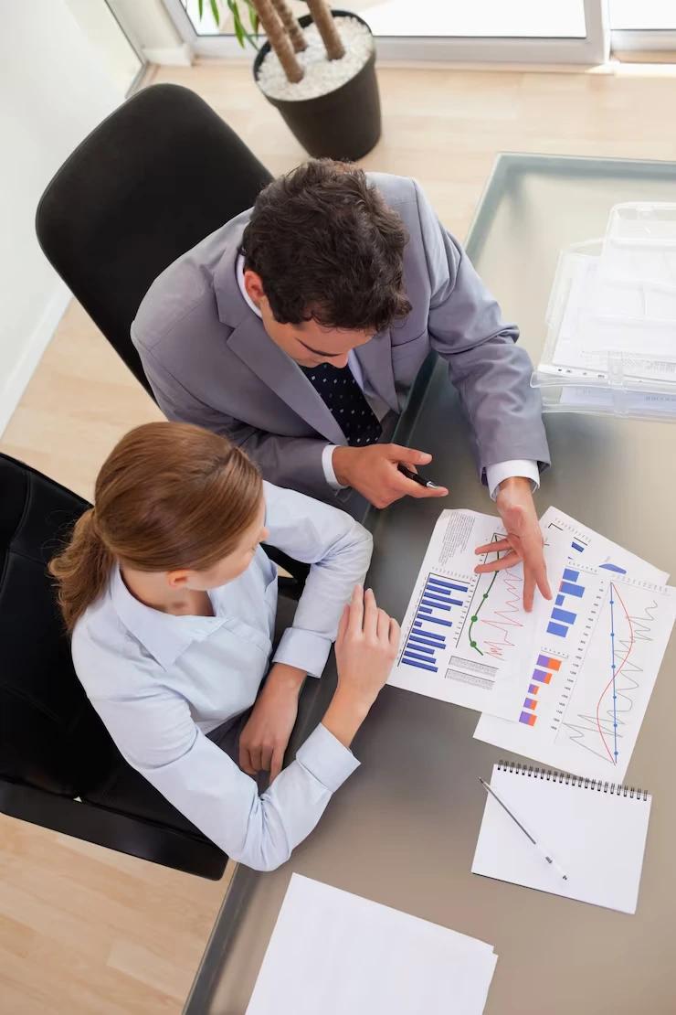 Investment advisor pointing to colorful charts and graphs while explaining market data to client