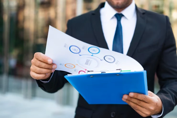 Business professional in suit holding blue folder with property investment charts and analysis documents