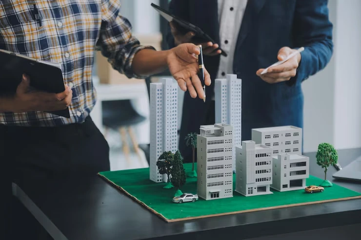 Property professionals discussing development plans using architectural model with miniature buildings