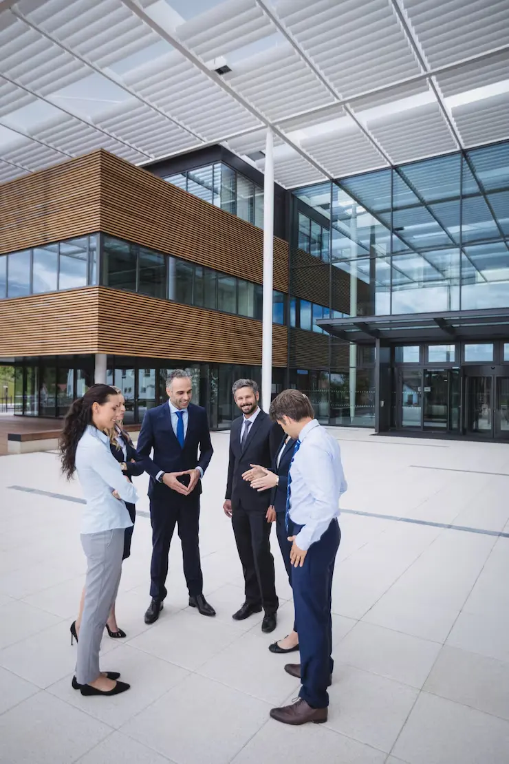 Business professionals conducting commercial property site inspection outside modern office building