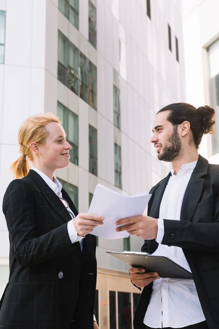Property professionals reviewing contract documents outside modern apartment building development