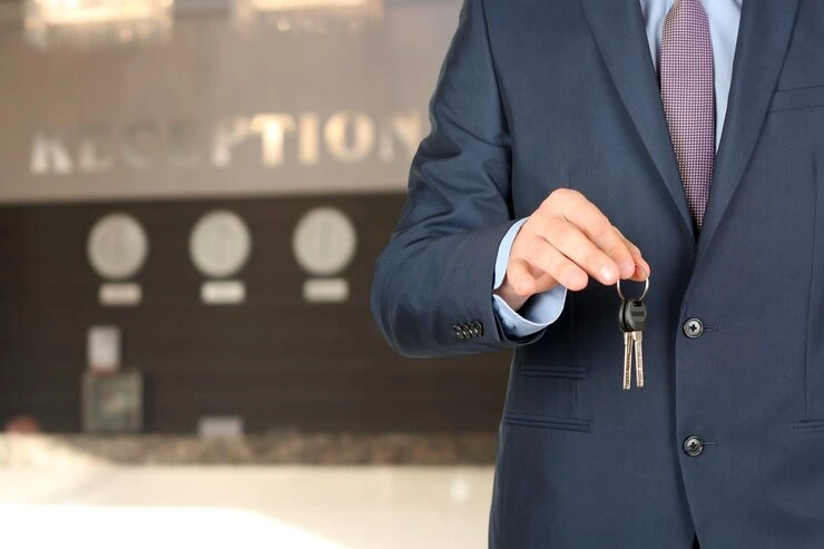 Property professional in suit holding keys outside luxury reception area after successful acquisition