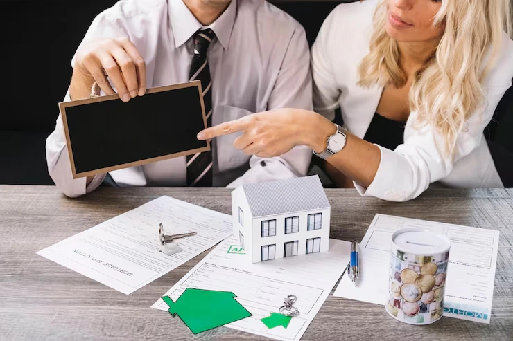 Property advisors presenting investment analysis using tablet, house model, and financial documents