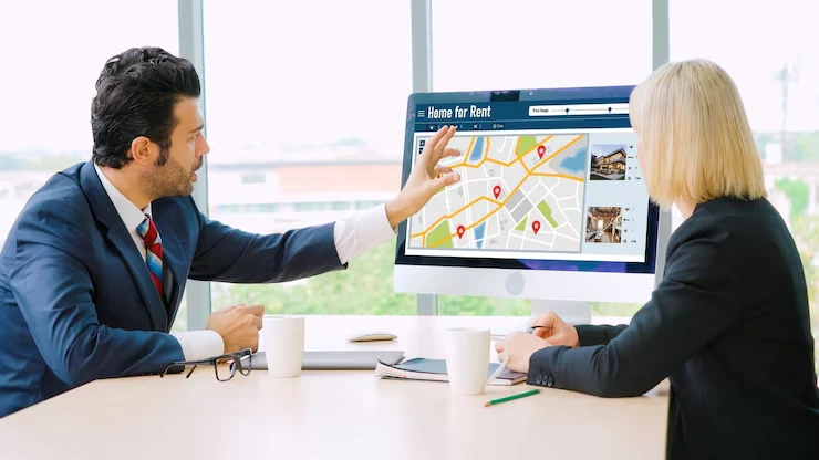 Property scout pointing to rental listings and map locations on computer screen to client