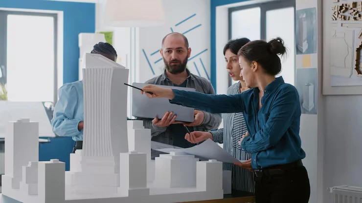 Three property analysts examining urban development models and market data in bright research office