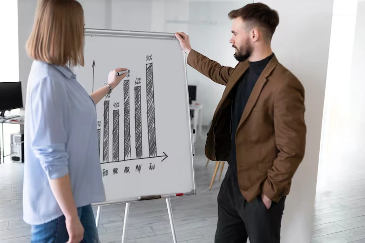 Property advisor presenting growth chart analysis to client using whiteboard in modern office