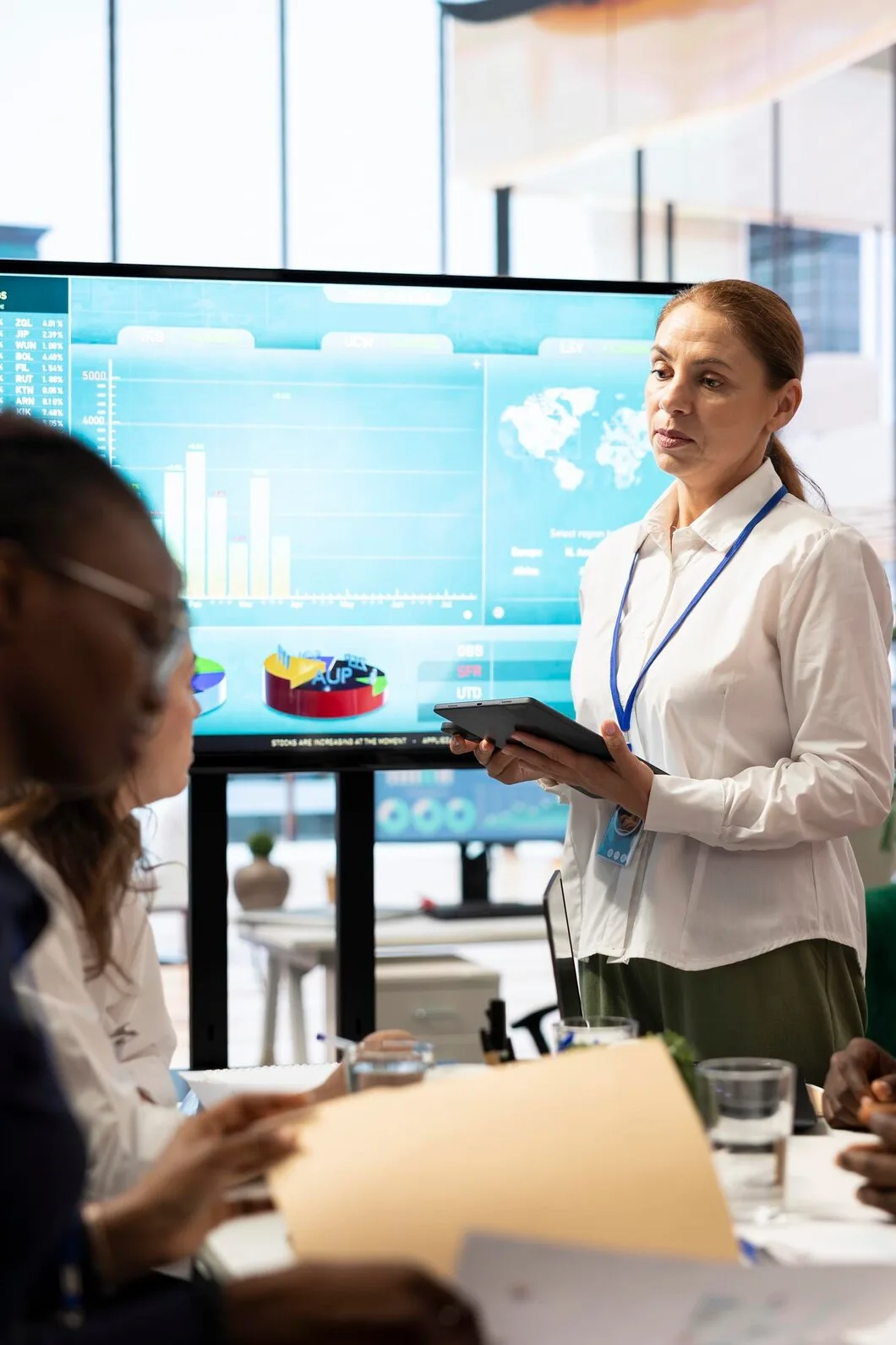 Property analyst presenting market data charts and regional performance metrics on large display screen