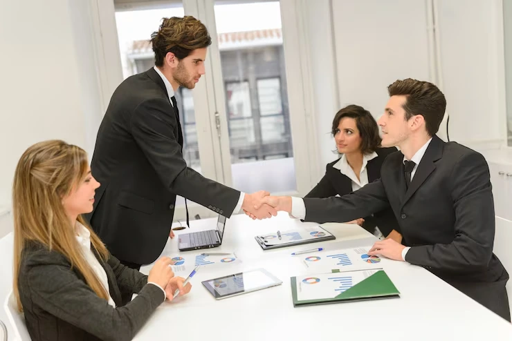 Property professionals shaking hands over negotiation table with financial documents and charts