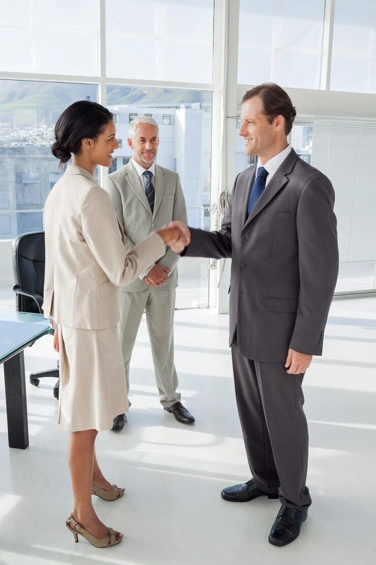 Business professionals completing property deal handshake in modern office overlooking city skyline