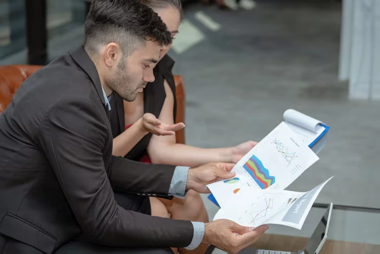 Property consultant reviewing detailed investment charts and graphs with client in modern office setting