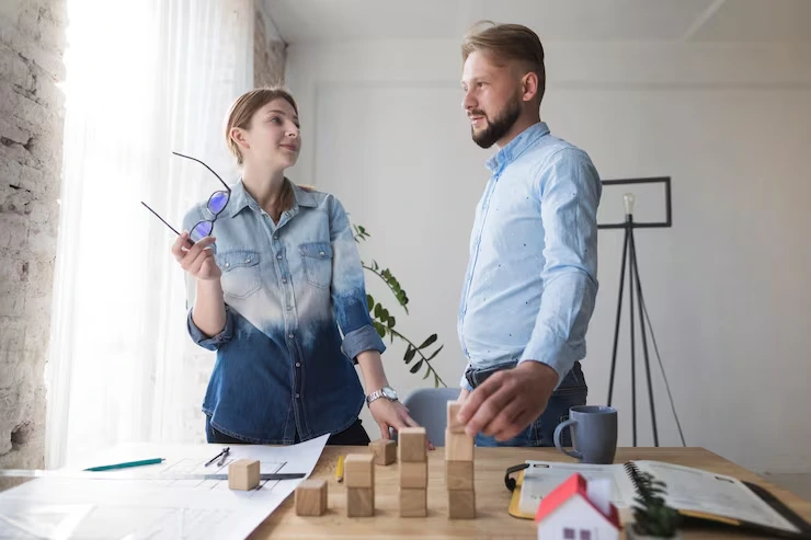 Property renovation consultants discussing improvement plans using wooden blocks and architectural drawings