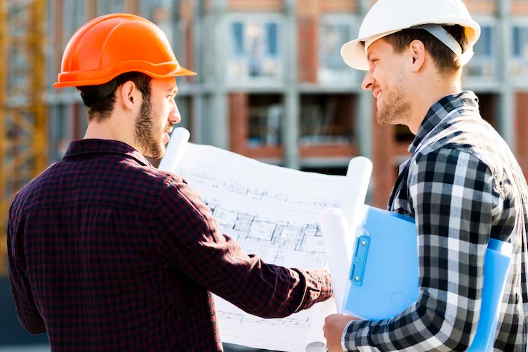 Two construction professionals reviewing building blueprints at active development site in Birmingham