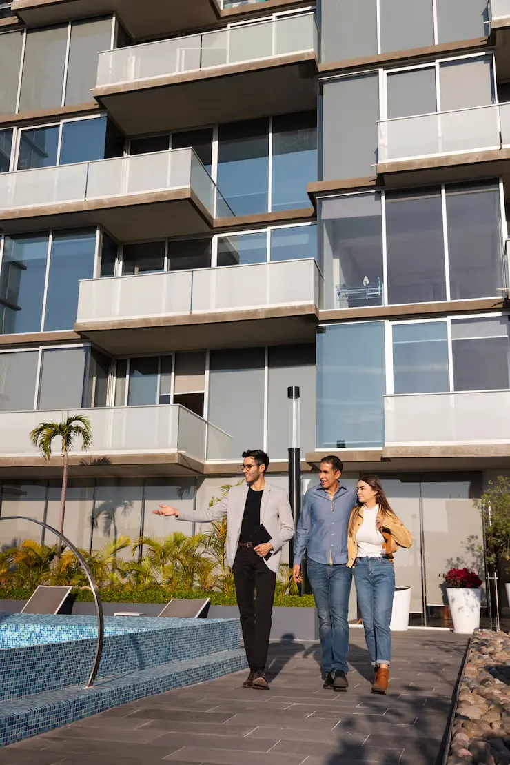 Property agent showing modern apartment complex with pool area to potential commercial investors