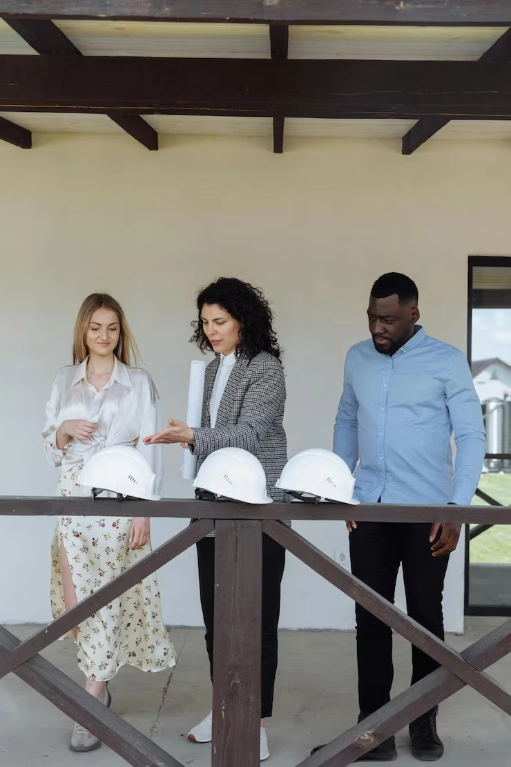 Three property professionals with hard hats conducting site inspection on covered terrace of development project