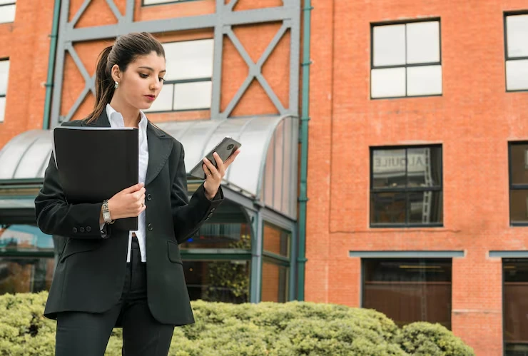 Professional property consultant reviewing mobile data outside modern residential development building